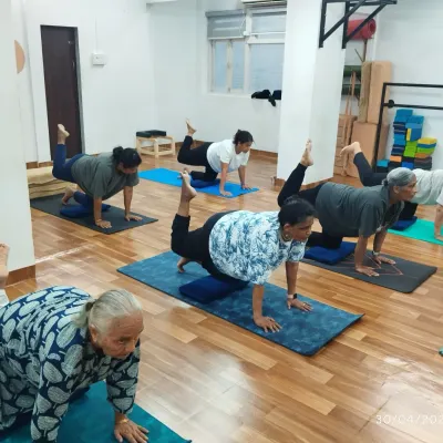 Our Golden Age Yoga class is all about joyful living. Here, our senior members practice a gentle leg lift to improve balance and core stability.