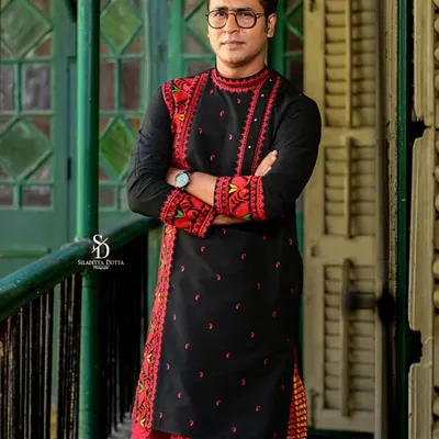 A strong, confident portrait of the groom in a striking black and red embroidered kurta. The traditional attire is given a modern edge with this powerful pose.