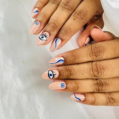A beautiful example of hand-painted evil eye nail art. This set combines different eye designs with abstract blue waves on a nude base.
