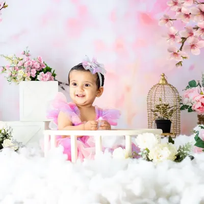 A dreamy fairy-tale scene with a beautiful little girl in a pastel dress. The cherry blossom backdrop and fluffy clouds create a magical, ethereal atmosphere.