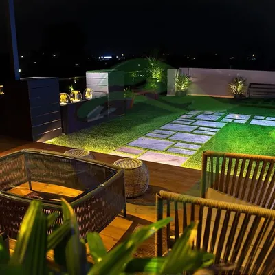 A terrace can become your private sanctuary, especially at night. We designed this space with a cozy seating area, a functional bar, and a beautiful lawn with stone pathways, all illuminated by soft lighting to create a magical ambiance.