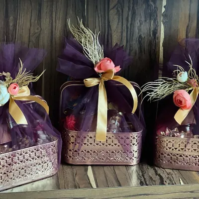 A trio of luxurious Diwali hampers wrapped in deep purple tulle with gold ribbons and floral accents. These are perfect for premium client gifting during the festive season.