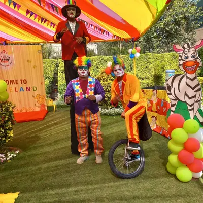 We provide a complete carnival package, including entertainers. This setup features a stilt walker and a clown on a unicycle, perfect for interacting with guests at a family day or kids' party.