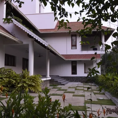 The estate house for Mr. Alex in Thrissur features expansive verandas supported by classical columns. This design provides ample shaded outdoor living area and reflects traditional Kerala architectural styles, adapted for modern living.