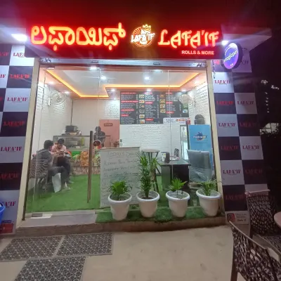 Here's a look at my cozy eatery at night. I've created a clean and bright space for you to enjoy all your favorite vegetarian snacks, from Vada Pav to Chole Bhature. I'm located right near the Bhartiya city back gate, making it an easy stop for your evening cravings.