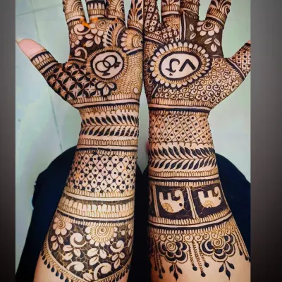 An intricate engagement mehandi featuring the couple's initials "VJ" and interlocking rings, a classic symbol of union. The design is filled with dense, traditional patterns.