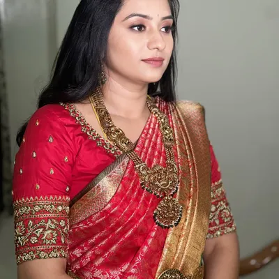 Embracing timeless elegance with a dewy, minimal look. This bride's natural glow is the star, enhanced with soft makeup. Her royal red silk saree and temple jewellery are perfectly complemented by soft, loose waves.