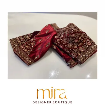 The sleeve of a traditional red velvet bridal blouse, showcasing dense floral embroidery. This is a classic choice for brides who want a look of pure regality for their Lagna Sohala.