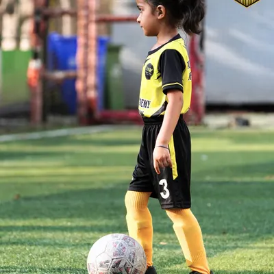 A young girl stands confidently with her foot on the ball, ready for her training session. I welcome players of all ages and genders, starting from the very basics.