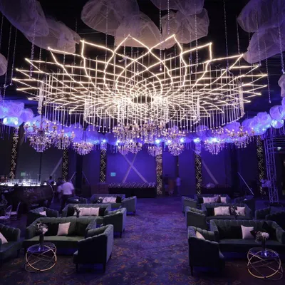 A custom-designed geometric lighting installation creates a breathtaking centerpiece for a large-scale corporate gala. This setup, featuring plush velvet seating and ambient purple lighting, demonstrates our ability to transform large venues into immersive, high-end environments.