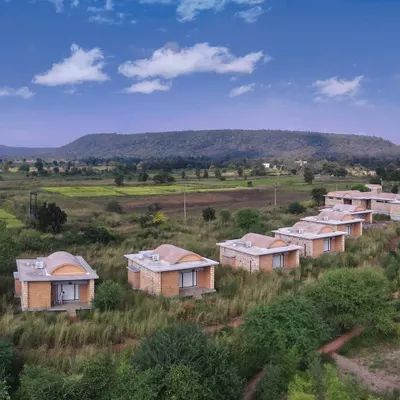 An aerial view of the cottages at Waghoba Ecolodge, nestled in the grasslands near Tadoba. The buildings, with their vaulted roofs made of conical pottery tiles, are designed to merge with the landscape's natural contours and hues.