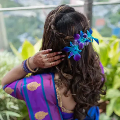 A beautiful look for a baby shower. The makeup is soft and glowing, with a braided hairstyle adorned with fresh orchids.
