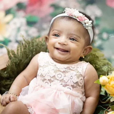 What a heart-melting smile. This baby girl, dressed in a delicate pink lace outfit, is surrounded by yellow flowers for her milestone portrait.