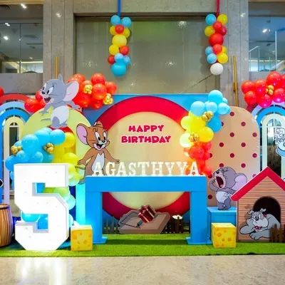 A fantastic Tom & Jerry birthday stage, complete with character cutouts, a light-up number '5', and themed props like a doghouse and cheese blocks.