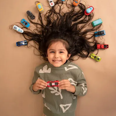 A fun and creative portrait of a little boy with his favorite toy cars arranged in his hair. This shot is a perfect way to capture his personality and what he loves at this age.