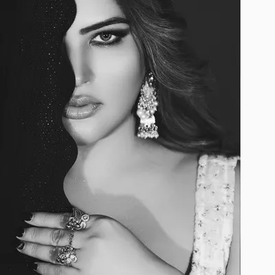 A powerful black and white close-up, using a dark fabric to frame one side of the face. This creates a high-contrast, artistic beauty shot that emphasizes the eyes and jewelry.