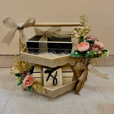 A beautiful two-tiered wooden stand used for wedding gift presentation, adorned with Jo Malone boxes and delicate floral arrangements. This is part of my 'Shaadi ke Tohfe' service.