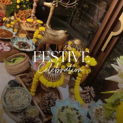 A festive celebration table adorned with yellow marigolds and brass decor. The spread includes a variety of Indian and fusion dishes, perfect for a Teej or Mehendi function.