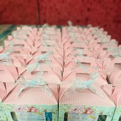 A large order of baby shower return gifts. These charming pink floral boxes are filled with small tokens of thanks for guests.