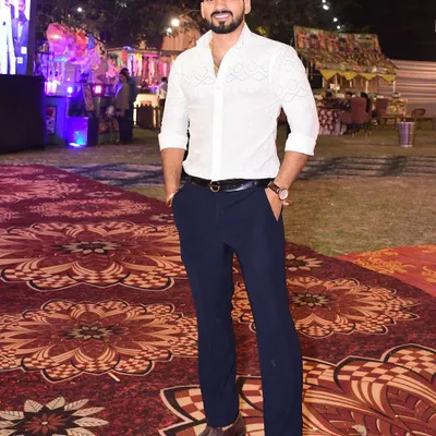 A valued client looking sharp and elegant at a wedding event in a custom-designed white shirt. The intricate detailing on the shirt adds a touch of bespoke luxury to his formal look.