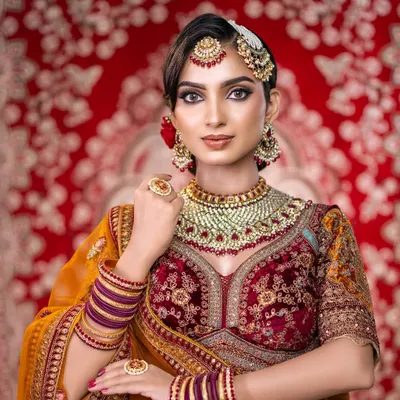 A regal North Indian bridal portrait. This image captures the intricate details of the makeup, from the sharp cut-crease eye to the perfectly blended base, complementing the rich colors of the lehenga.