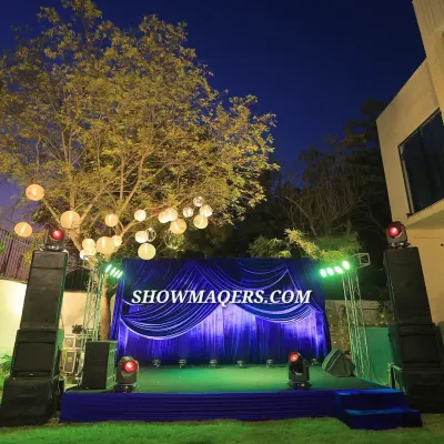 An outdoor stage setup for a corporate retirement party. The royal blue draping, professional trussing with spotlights, and sound system created a perfect setting for speeches and entertainment under the stars.