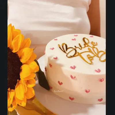 Such a cute 'Bride to Be' cake. This one has a clean white frosting base with tiny hand-painted hearts and a gold acrylic topper for a modern, sweet look.