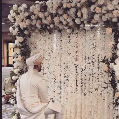 Making your Nikaah ceremony picture-perfect. This elegant setup features a backdrop of white floral strings (mogra) and a lush arch of white roses, creating a serene and beautiful atmosphere for the groom.