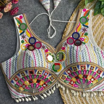 This is one of my favorite statement blouses. The combination of multi-color threadwork, mirror embellishments, and cowrie shell details makes it a standout piece you can pair with many different skirts.