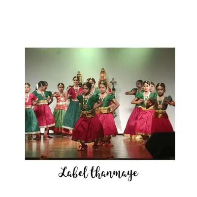 A group of young dancers performing in traditional Bharatanatyam costumes, featuring classic color combinations of green, pink, and red.