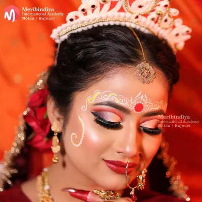 A detailed close-up of the Bengali bridal makeup, focusing on the intricate white and red chandan and kumkum designs that adorn the forehead.