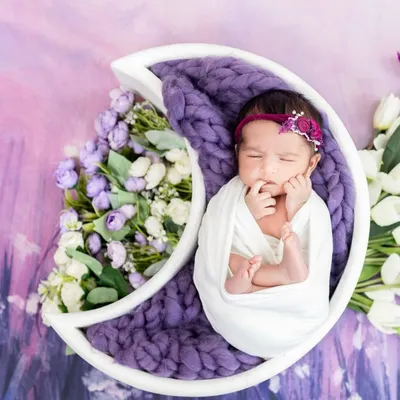 A beautiful newborn portrait using our celestial moon prop with a purple floral arrangement. We have a wide variety of props to create a dreamy setting for your baby.