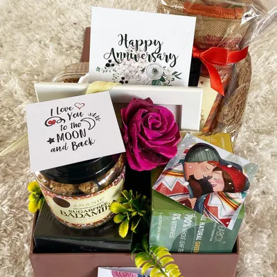 Celebrate your journey together with a romantic anniversary hamper. This gift box is filled with love, featuring sugar-free sweets, a "Happy Anniversary" card, a personal "I Love You to the Moon and Back" note, and other curated items to make your special day even more memorable.