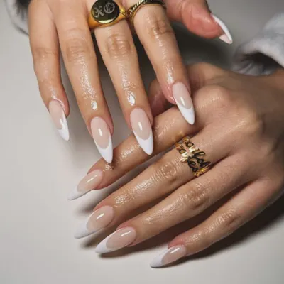 A classic French manicure on long, elegant stiletto-shaped nail extensions. The sharp white tips create a dramatic and sophisticated look.