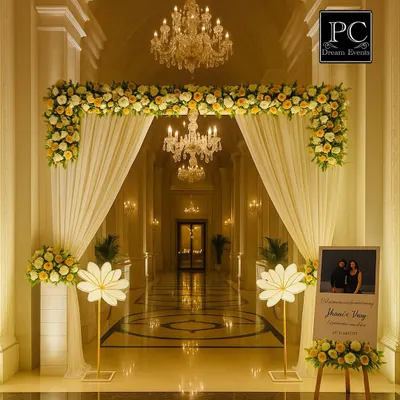 An absolutely regal entrance for an engagement ceremony. I used a floral arch with white drapes, set in a grand corridor with crystal chandeliers, to create a breathtaking welcome for the guests.