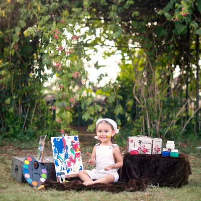 A little artist with a very happy, paint-covered smile. This outdoor painter theme is a fantastic way to capture a toddler's creative and messy side in a beautiful garden setting.
