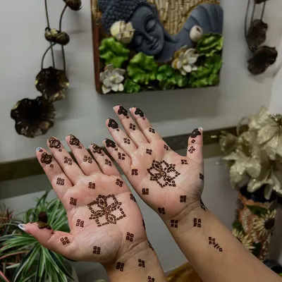 A perfect example of minimal henna for the Teej festival. This design features a simple lotus motif in the center of the palm with small, delicate patterns on the wrist and fingers.