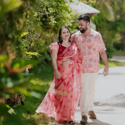 A romantic stroll through a beautiful resort garden. The coordinated floral and pink outfits of the couple complement the lush surroundings.