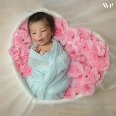 Even when they're awake, we can capture beautiful moments. This little one is nestled safely in a heart-shaped floral basket, a popular setup for our artistic newborn photography.