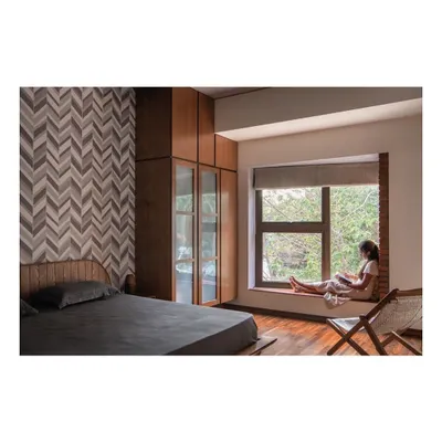 A bedroom featuring a suite of custom furniture. The floor-to-ceiling wardrobe provides ample storage with wood and glass doors, while the bed's unique headboard and the integrated window seat create a cohesive and tranquil environment.