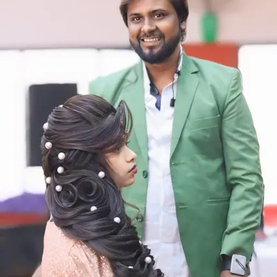 A beautiful party hairstyle with intricate twists and soft waves, decorated with pearls. I am standing proudly next to my creation.