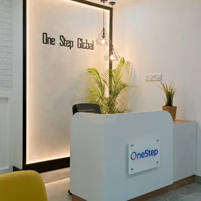 The reception area we designed for Onestep Global's first office in Bangalore. The backlit feature wall with the company logo, modern pendant lights, and a pop of color from the yellow armchair create a welcoming and professional first impression.