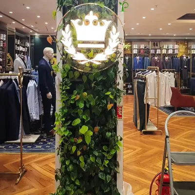 For this Louis Philippe store, I wrapped a central pillar in lush, trailing plants to surround their logo with natural elegance. This biophilic touch elevates the brand's premium feel and creates a memorable feature in the retail space.