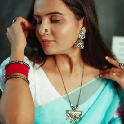 A beautifully detailed shot focusing on a pair of traditional silver jhumkas and a matching necklace. The shallow depth of field draws the eye directly to the jewelry.