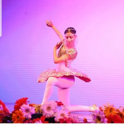 A solo performance from a classical ballet production, surrounded by flowers. The stage has always been a special place for me, and I use my experience as a professional ballerina to guide my students in their own artistic expression.