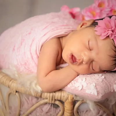 Prettiness in pink. A classic newborn portrait featuring a soft pink wrap, a delicate floral headband, and a peacefully sleeping baby. This style is timeless and always beautiful.