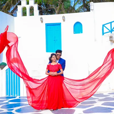 A dramatic shot using a flowing red gown against a beautiful Santorini-themed backdrop. My packages include a variety of gowns like this to make your pre-wedding photos truly stand out.