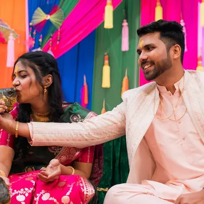 A playful moment from a pre-wedding ceremony, as the groom helps the bride with a ritual.