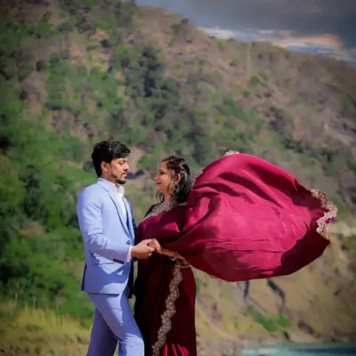 A cinematic shot of a couple against the backdrop of the Rishikesh mountains, with the bride's saree flowing in the wind.