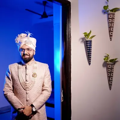 A stylish portrait of the groom in his wedding sherwani, ready for the big day. The blue backlighting adds a modern, cinematic touch.